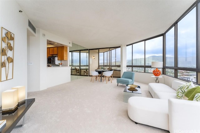 living area with light carpet, visible vents, and a mountain view