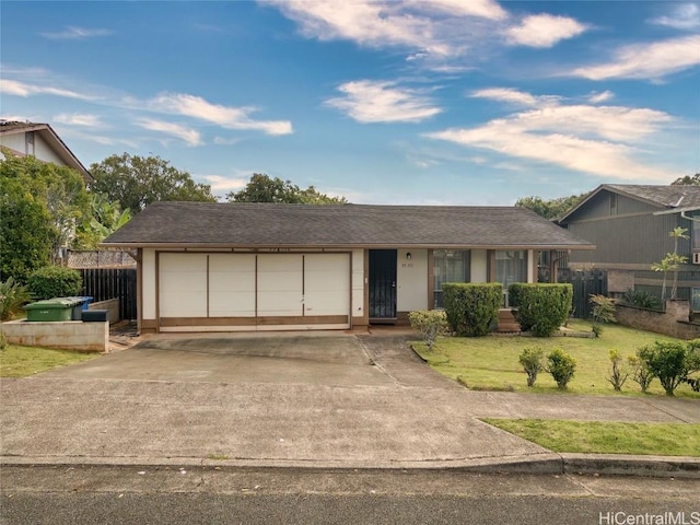 ranch-style home featuring an attached garage, fence, concrete driveway, and a front yard