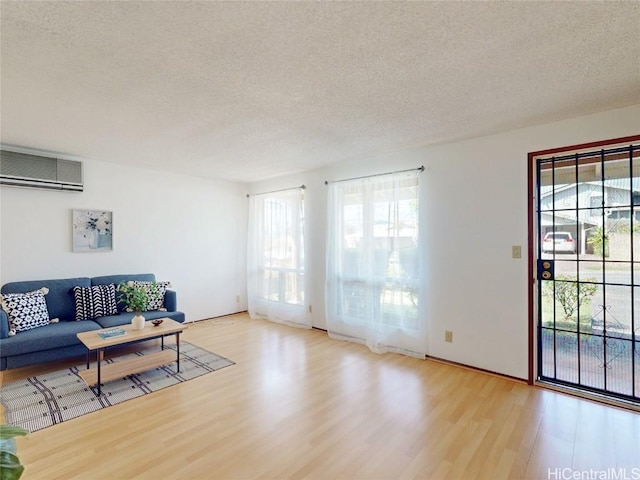 living room featuring a textured ceiling, an AC wall unit, and wood finished floors