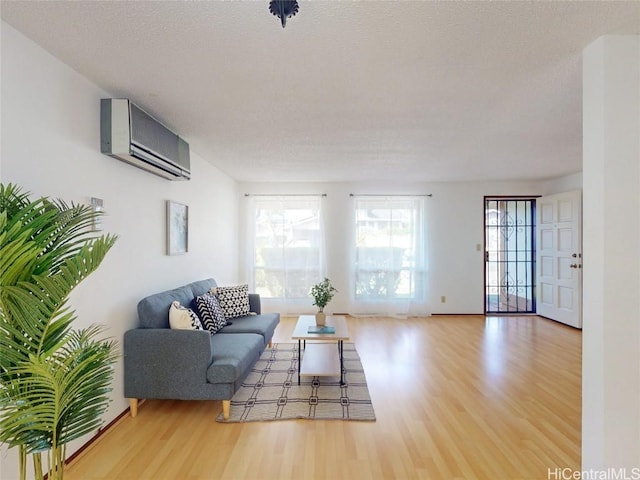 living room featuring a textured ceiling, an AC wall unit, and wood finished floors