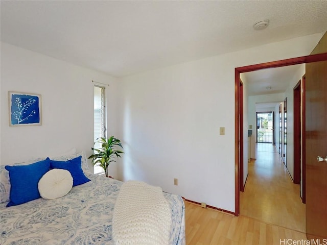 bedroom featuring light wood finished floors and baseboards