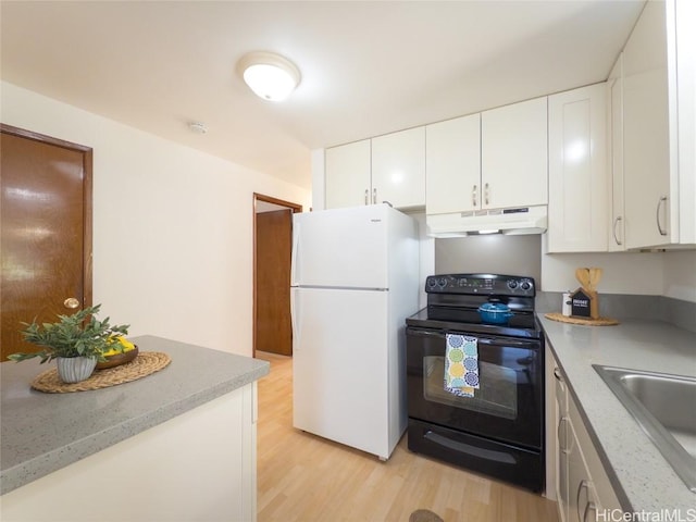 kitchen with under cabinet range hood, electric range, a sink, light wood-type flooring, and freestanding refrigerator