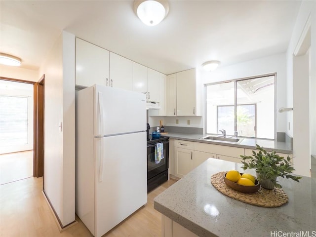 kitchen with black electric range, freestanding refrigerator, white cabinets, a sink, and under cabinet range hood