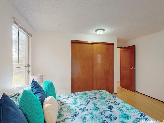 bedroom featuring light wood-style flooring, a textured ceiling, and a closet