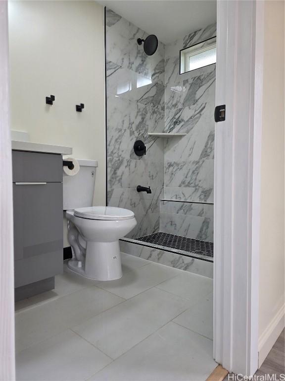 full bath with toilet, a marble finish shower, and vanity