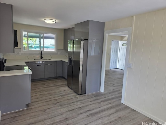 kitchen featuring electric range, a sink, light countertops, gray cabinets, and stainless steel fridge