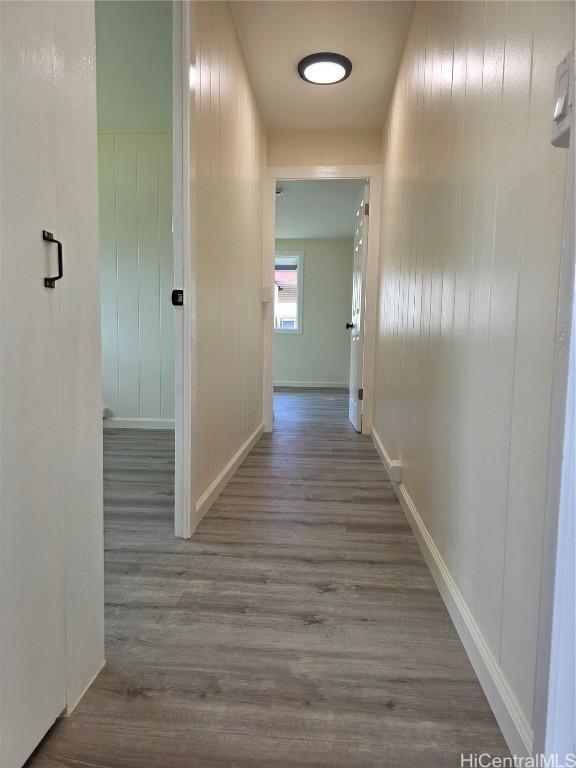 corridor featuring baseboards and wood finished floors