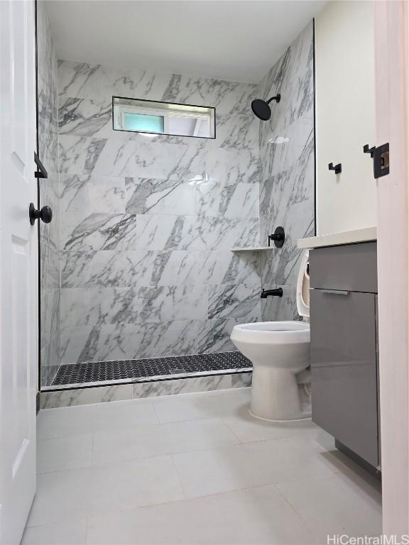 full bathroom featuring toilet, a tile shower, and vanity