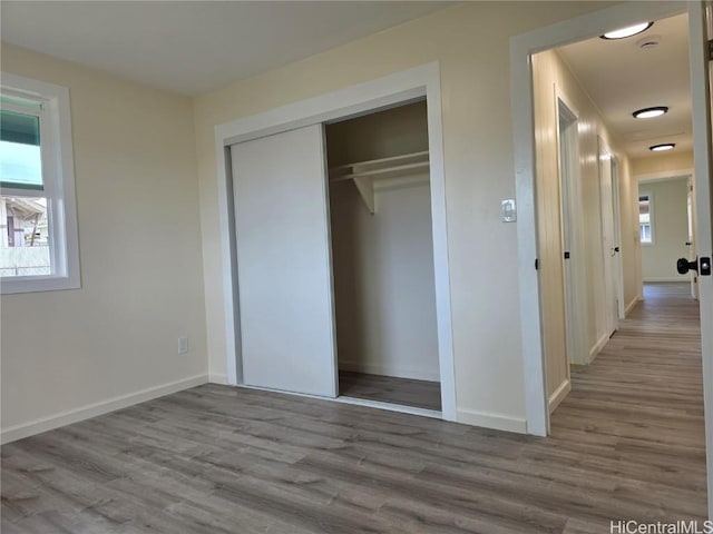 unfurnished bedroom featuring multiple windows, a closet, and wood finished floors