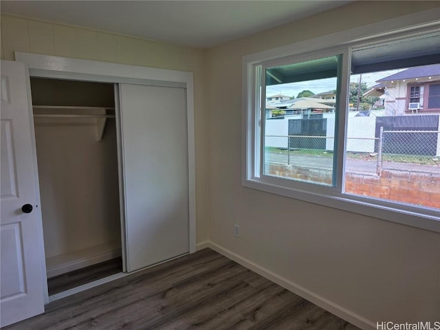 unfurnished bedroom featuring baseboards, a closet, and wood finished floors