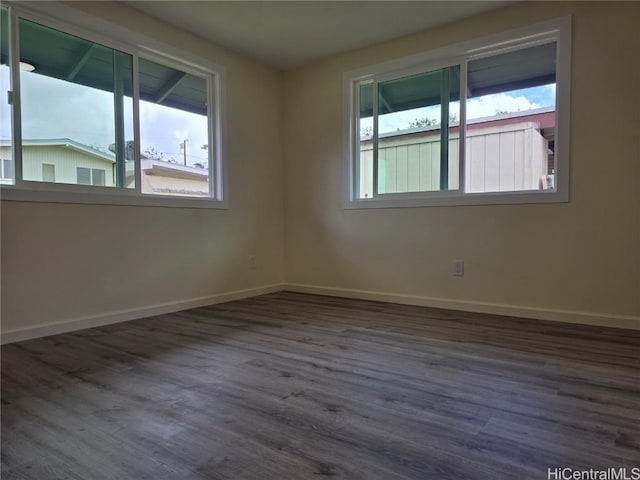 spare room with baseboards and wood finished floors