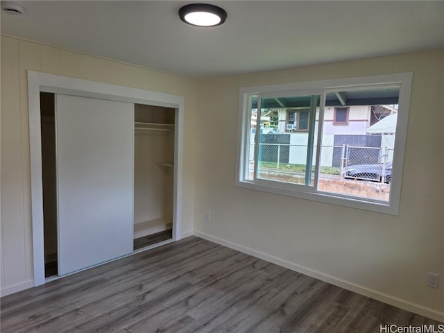 unfurnished bedroom with a closet, baseboards, and wood finished floors