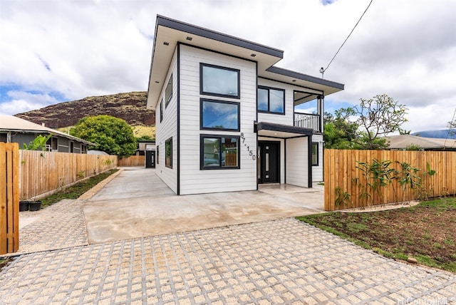 view of front facade featuring a fenced backyard, a patio, a balcony, and a mountain view