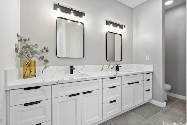 bathroom featuring double vanity, a sink, baseboards, and tile patterned floors