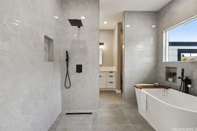 full bath with a freestanding tub, vanity, tile walls, a tile shower, and tile patterned floors