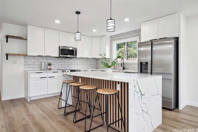 kitchen featuring appliances with stainless steel finishes, a sink, decorative backsplash, and open shelves