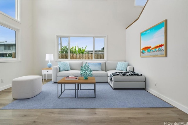 living area with a high ceiling, baseboards, and wood finished floors