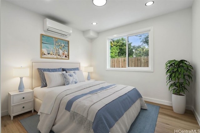 bedroom with recessed lighting, wood finished floors, baseboards, and a wall mounted AC