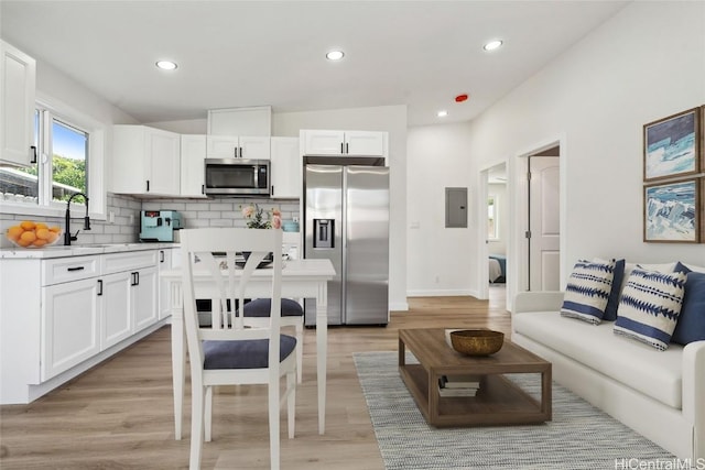 kitchen featuring electric panel, a sink, stainless steel appliances, light countertops, and backsplash