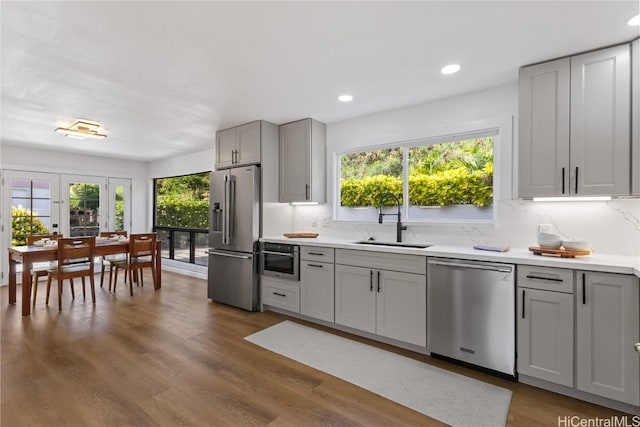 kitchen featuring a healthy amount of sunlight, appliances with stainless steel finishes, gray cabinets, and a sink