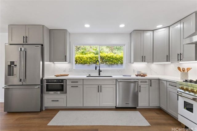 kitchen with dark wood-style floors, stainless steel appliances, light countertops, gray cabinetry, and a sink