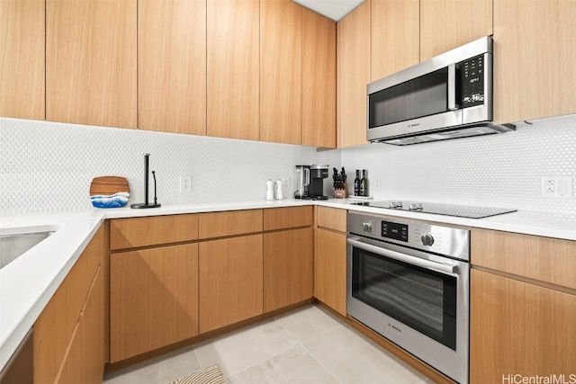 kitchen featuring stainless steel appliances, light countertops, decorative backsplash, and light tile patterned floors