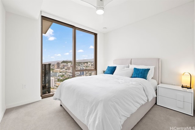 bedroom with ceiling fan, a view of city, light carpet, access to exterior, and expansive windows