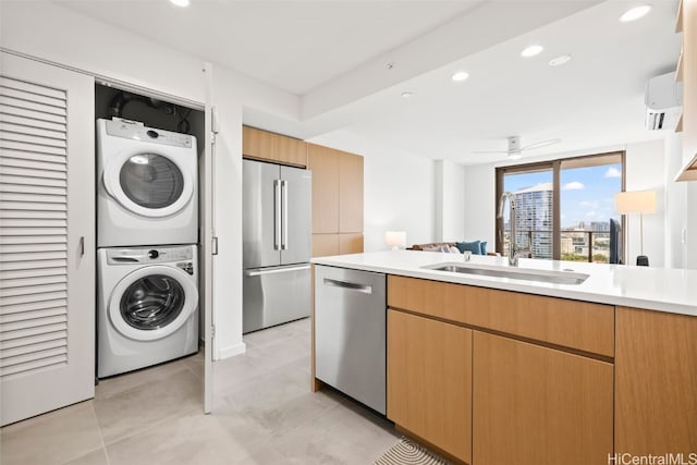 kitchen with stainless steel appliances, recessed lighting, light countertops, a sink, and stacked washing maching and dryer