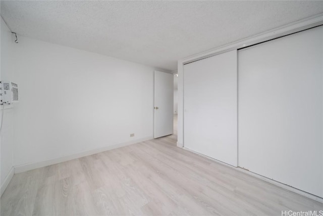 unfurnished bedroom with a closet, baseboards, a textured ceiling, and wood finished floors