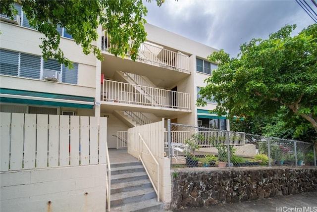 view of building exterior featuring fence and stairway