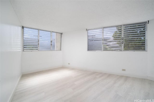 unfurnished room featuring a textured ceiling, baseboards, and wood finished floors