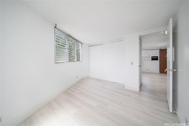 empty room featuring light wood-type flooring and concrete block wall