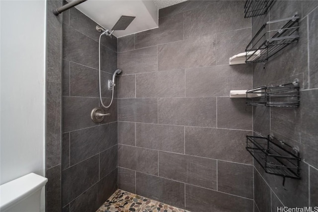 full bathroom with a tile shower and toilet