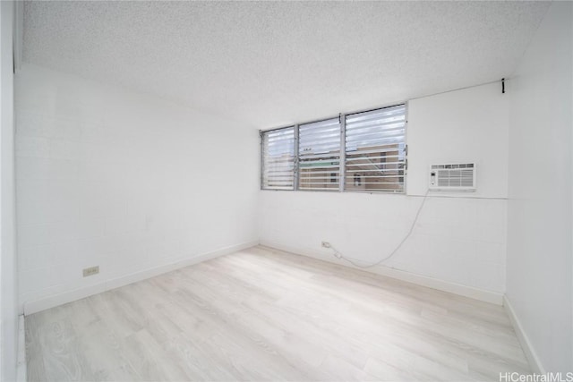 unfurnished room featuring a textured ceiling, baseboards, and wood finished floors