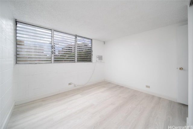 empty room with baseboards, a textured ceiling, and wood finished floors