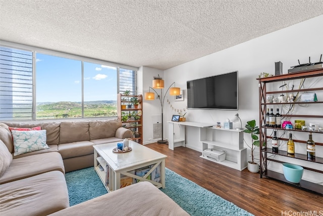 living room with a textured ceiling, baseboards, and wood finished floors