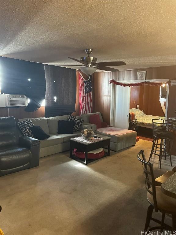 carpeted living room featuring a textured ceiling, an AC wall unit, and a ceiling fan