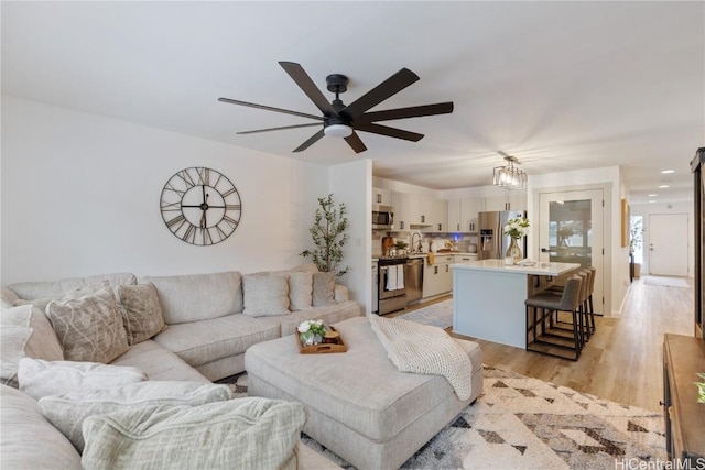 living room with light wood-type flooring and a ceiling fan