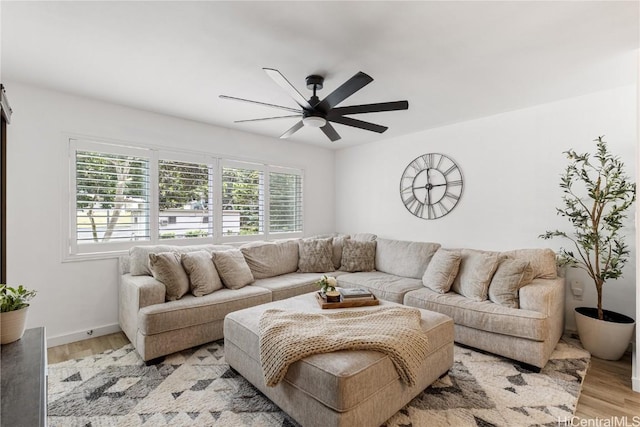 living room with light wood finished floors, baseboards, and ceiling fan