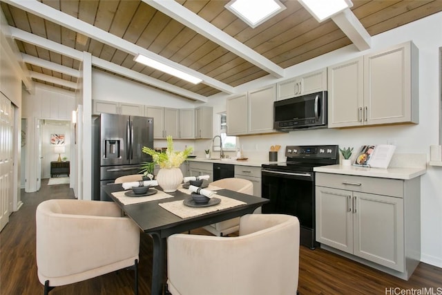 kitchen with vaulted ceiling with beams, black appliances, light countertops, and dark wood-style floors