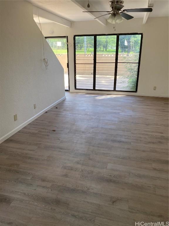 spare room with ceiling fan, beamed ceiling, baseboards, and wood finished floors