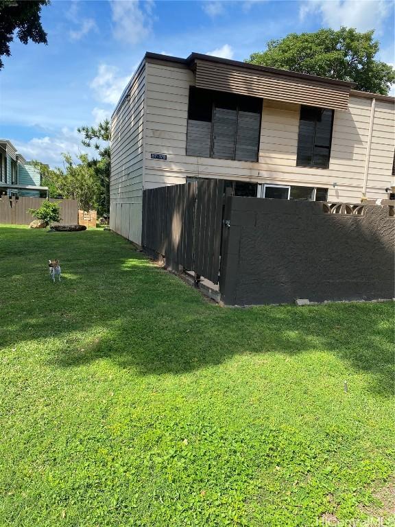 view of property exterior with fence and a lawn