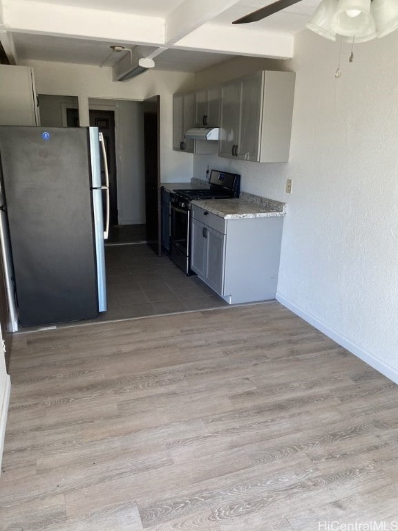 kitchen featuring baseboards, light wood-style floors, stainless steel appliances, gray cabinetry, and under cabinet range hood