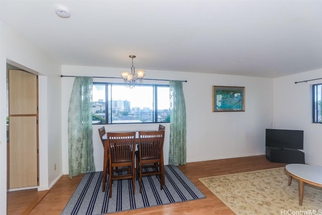 dining space with an inviting chandelier, plenty of natural light, and wood finished floors