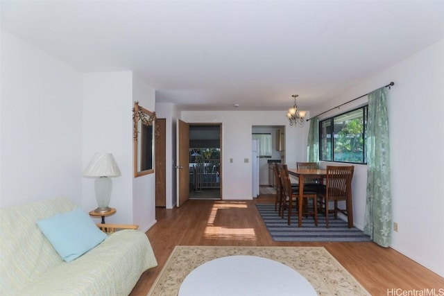 living room with a chandelier, baseboards, and wood finished floors