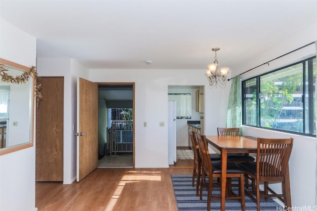 dining room featuring a notable chandelier, baseboards, and light wood finished floors