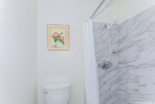 bathroom featuring toilet and a tile shower