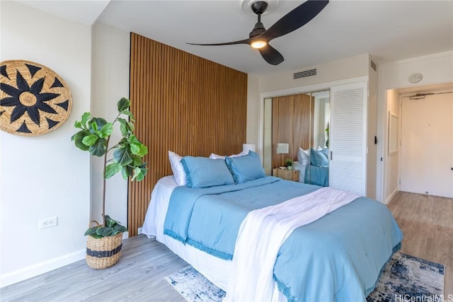 bedroom with ceiling fan, visible vents, baseboards, a closet, and light wood finished floors