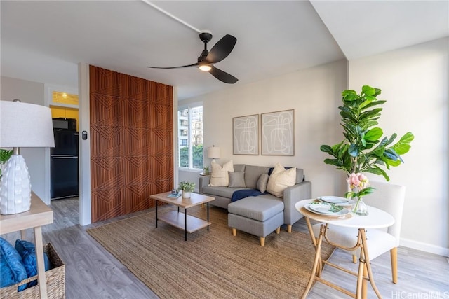 living area with ceiling fan, baseboards, and wood finished floors