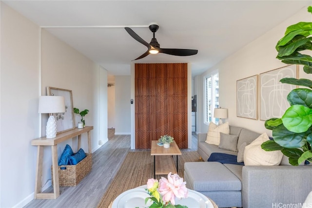 living room featuring ceiling fan, baseboards, and wood finished floors